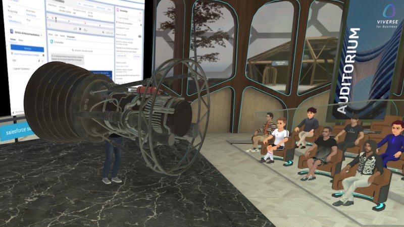 A gathering in an auditorium in VIVERSE with a 3D model on the stage next to the presenter.