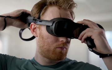 Man adjusting his VIVE XR Elite’s battery cradle with VIVE Controllers for XR Series in his hands regular