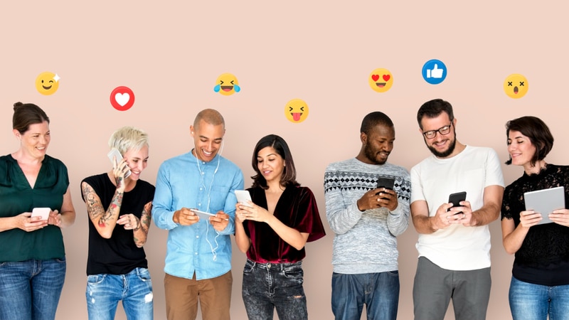 Seven people using their phones and tablet with overhead emojis representing social media reactions..png
